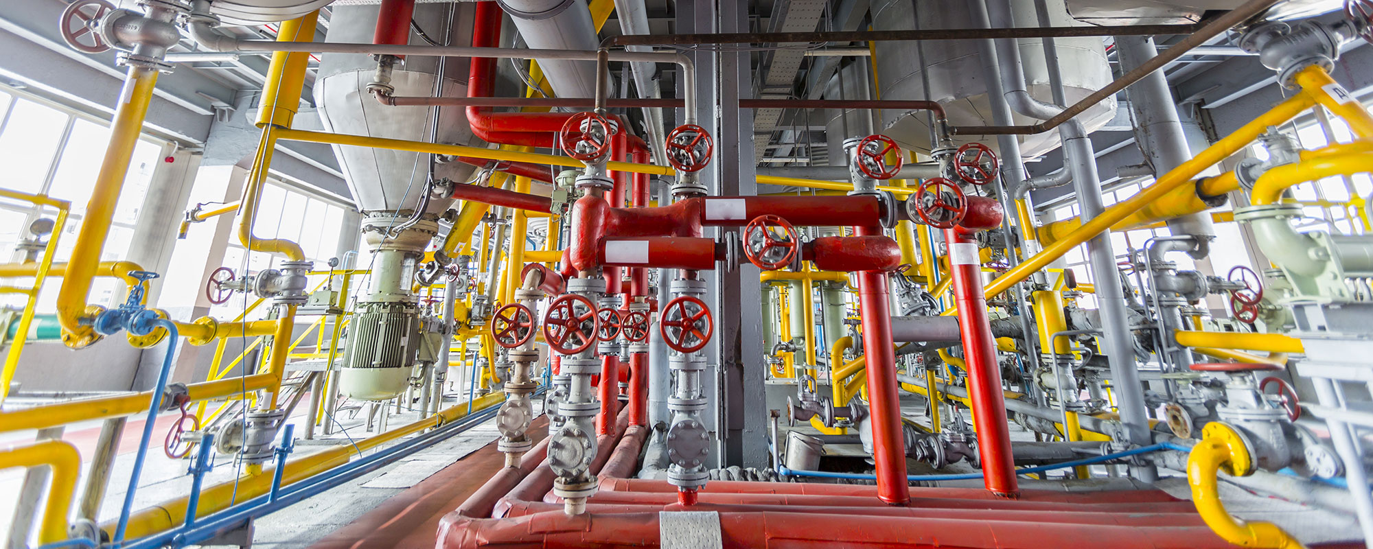 Red, yellow, and silver piping in an indoor industrial setting.
